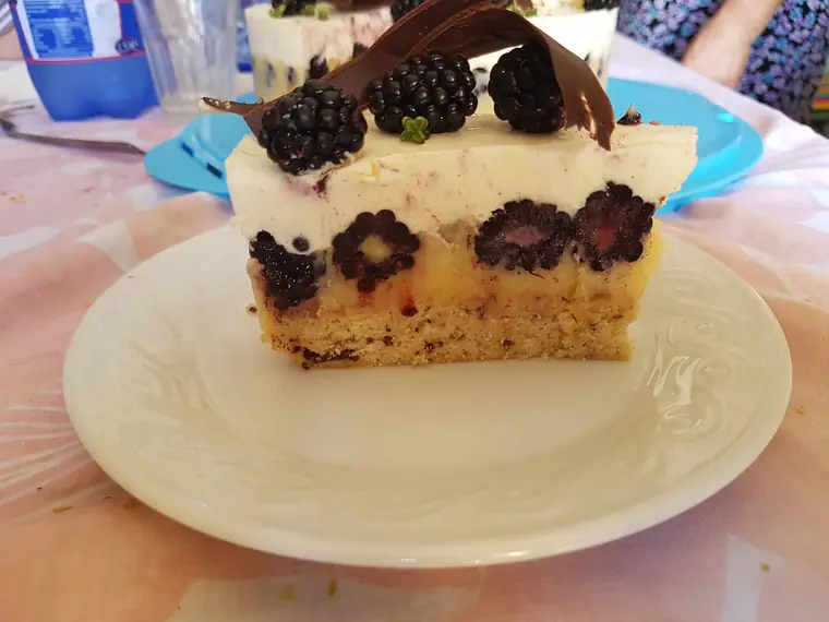 A slice of blackberry cake with fresh blackberries